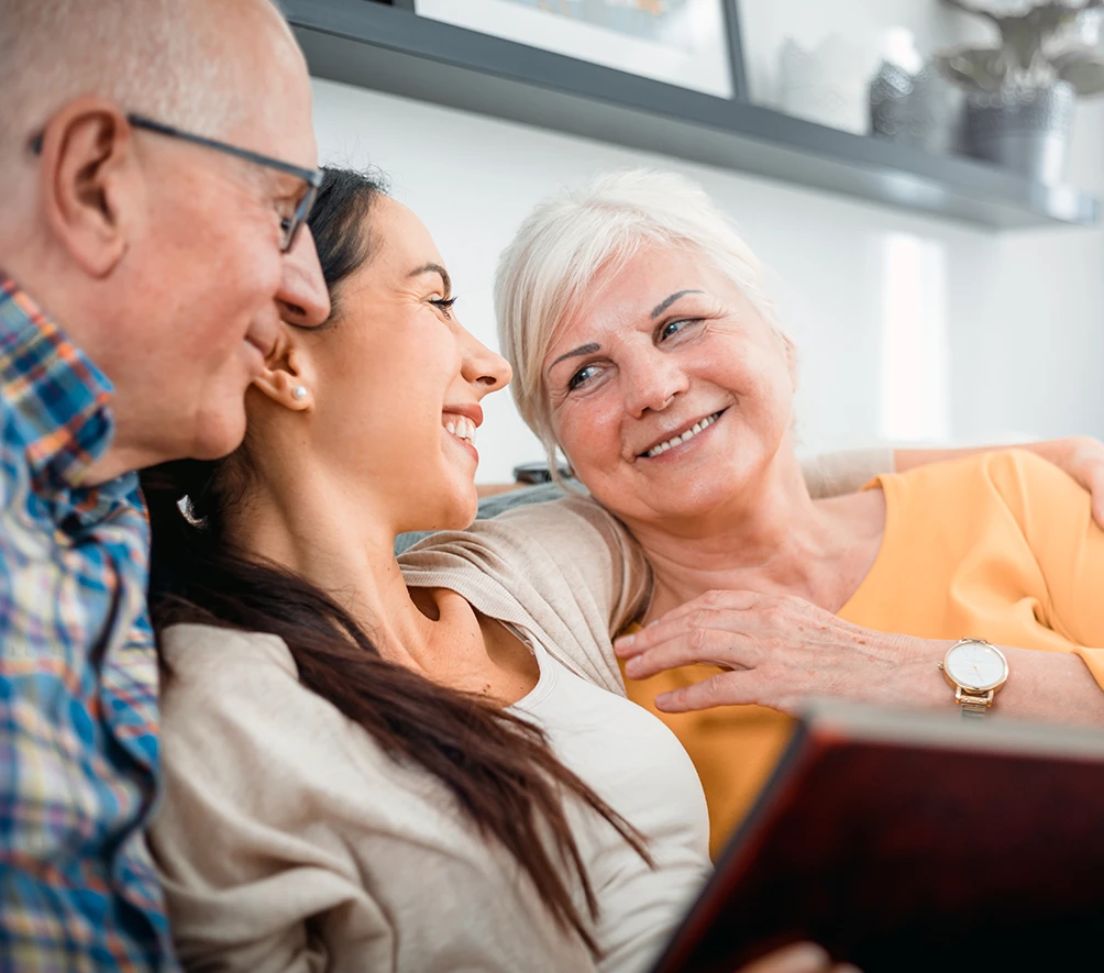 kid smiling with senior parents looking at memory book