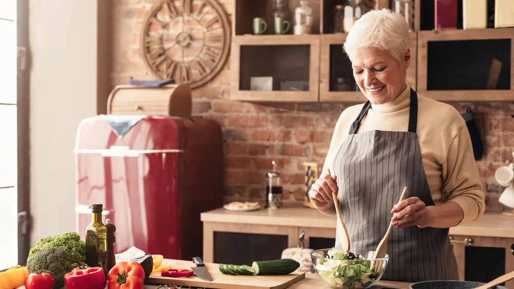 a woman making a salad in a kitchen