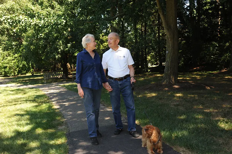 an older couple walking their dog on a path