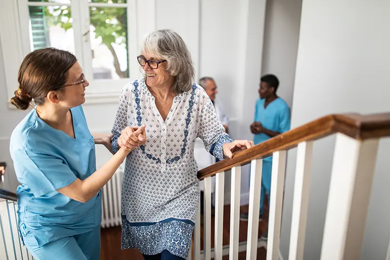 a care manager helping an older woman up the stairs