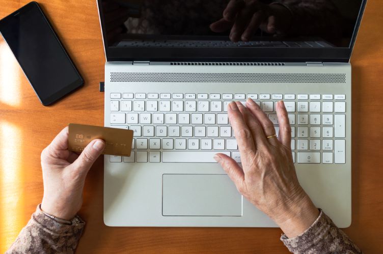 a person at a keyboard with a credit card in one hand