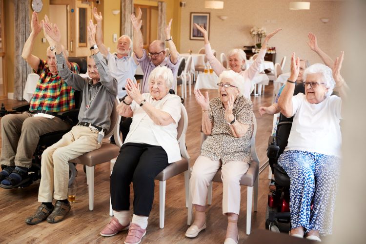 a group of elderly people doing chair exercises