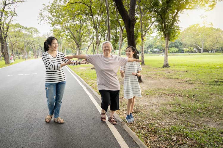 a man walking with his arms out with young girls on his sides to prevent him from falling