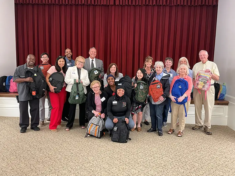 Waverly Heights staff and residents holding backpacks to donate to a school