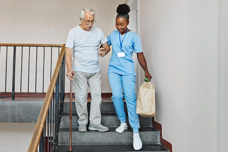 Geriatric care manager helping a man down stairs